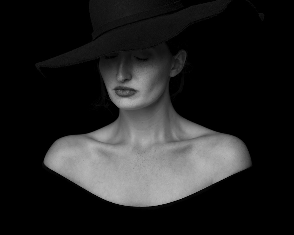 A woman wearing a black wide-brim hat in a studio portrait